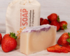 Bar of soap with strawberry scent on a background of strawberries.