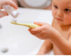 A person's hand is using the Tooth Powder Trial to pour tooth powder on Landon's toothbrush