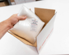 Hand placing Laundry Soap Refill into shipping box