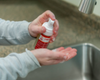 Person washing hands with liquid soap under running water in a sink