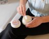 Goat milk lotion being applied from a lotion tub