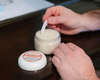Goat milk lotion being scooped from tub