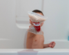 Landon in bath holding Goat Milk Bath bag