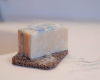 mega size white bar of soap with blue swirl on top sitting on soap rest