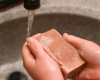 Hand holding a bar of soap under running water
