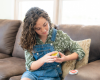 Applying balm to arm while sitting on a couch