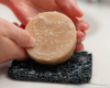 hands placing a luffa soap on soap rest