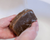 hands holding brown goat milk soap bar