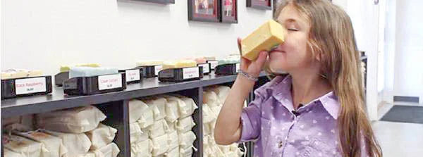 Young girl holding a bar of soap to her nose 