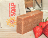 Bar of goat milk soap with a strawberry on a white background