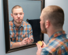 Fletcher looking in mirror and holding Beard Balm