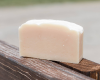 white bar of goat milk soap sitting on fence