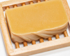 a yellow bar of soap sitting on a wood soap dish