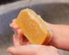 hands holding yellow bar of soap above grey sink