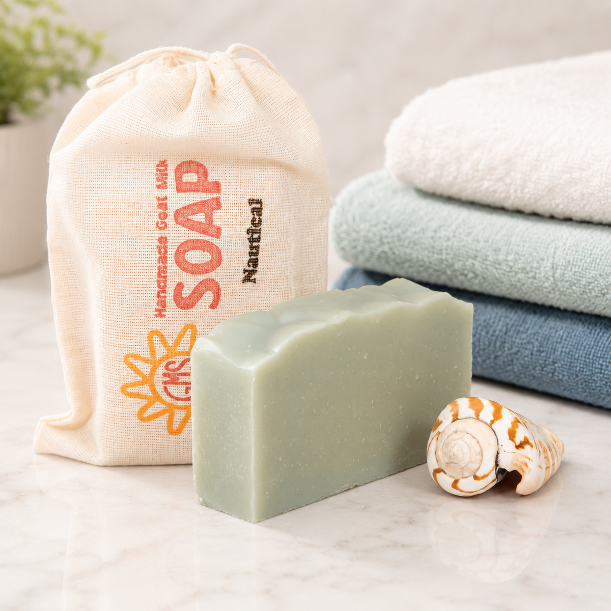 Bar of goat milk soap with a drawstring bag labeled 'Soap' and folded towels on a light surface.