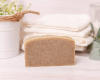 shampoo bar sitting on surface with washcloths and plant in background