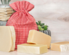 Assorted bars of goat milk soap with a red fabric pouch on a wooden surface.