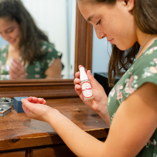 Woman applying goat milk stuff perfume in front of a mirror.