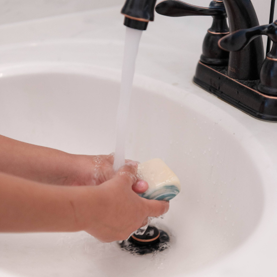 washing hands in sink with goat milk soap