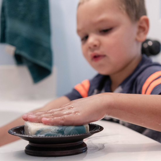 Landon washing hands with bar of goat milk soap