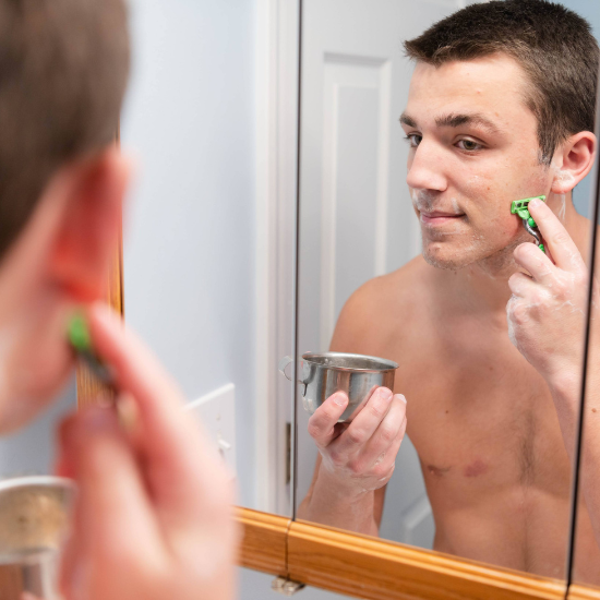 Hewitt shaving his beard in front of a mirror using the Shaving Goat Milk Soap

