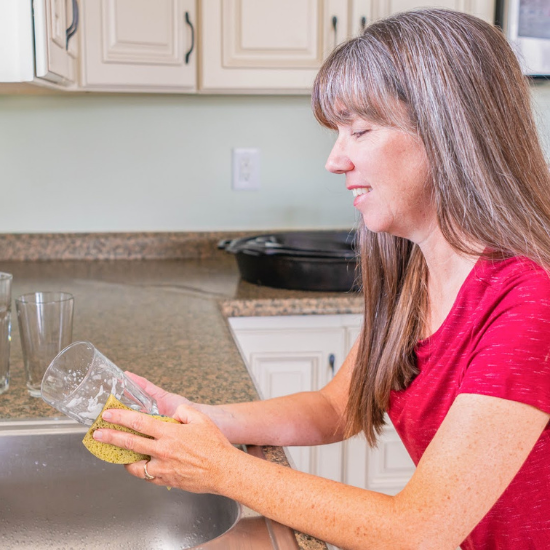 washing dishes at the sink with goat milk dishwashing soap