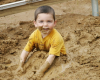 Child in yellow shirt playing in mud