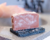 pink bar of goat milk soap on soap rest