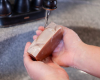 hands holding bar of goat milk soap above sink 