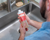 Emery looking at liquid soap refill bottle at kitchen sink