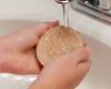 hands holding luffa soap under running water