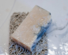 white bar of soap with blue swirl sitting on soap rest
