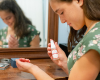 Woman applying Perfume in front of a mirror