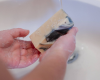 hands holding white bar of goat milk soap with black swirl
